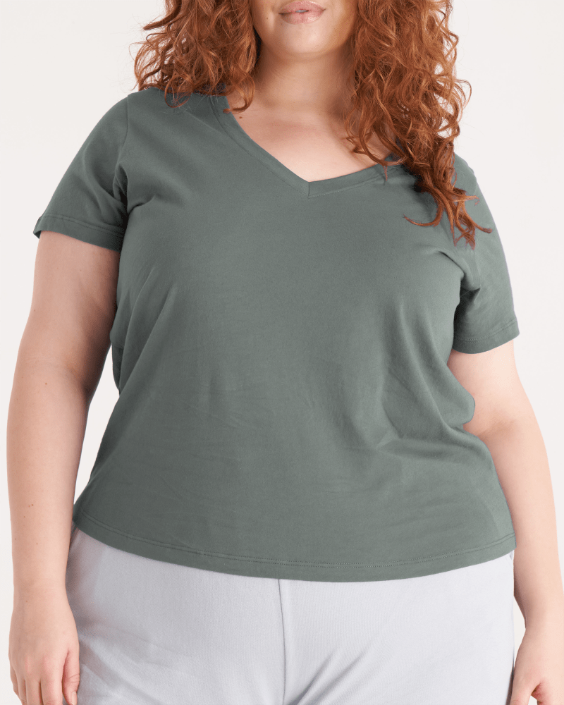 Front of a model wearing a size 1X The V Neck Tee in Thyme by The Standard Stitch. | dia_product_style_image_id:248753